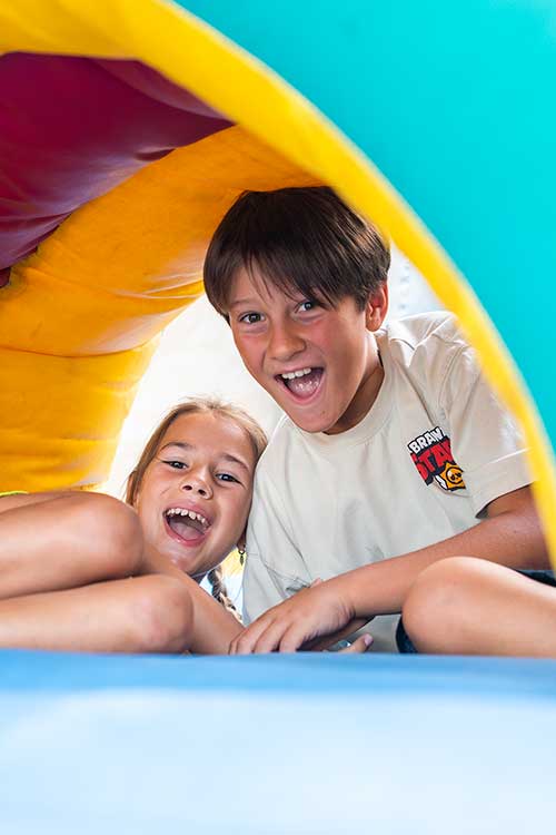 Kinder spielen auf den Hüpfburgen auf dem Spielplatz des Pappasole Camping Village.