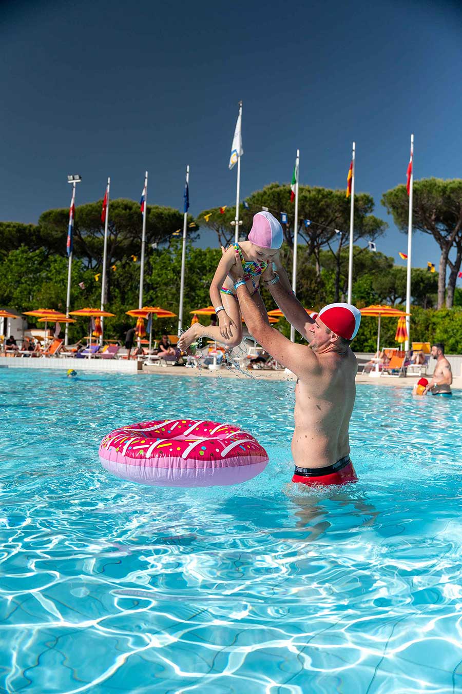 Vater und kleines Mädchen spielen im Pool mit einem aufblasbaren