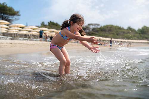 Kleines Mädchen spielt im Wasser vor dem Pappabeach Beach Resort