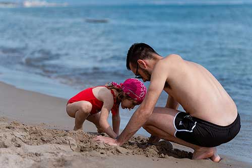 Vater und kleines Mädchen spielen am Ufer